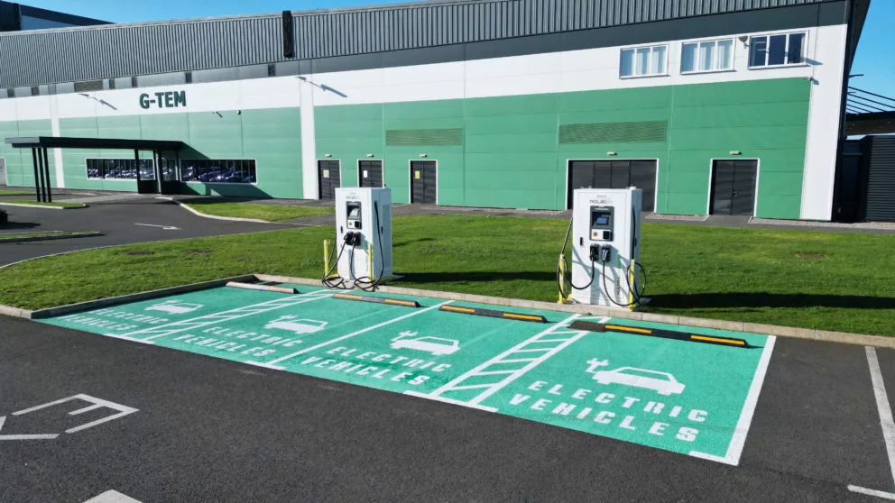 4 rapid charger bays for electric vehicles outside a large manufacturing production facility